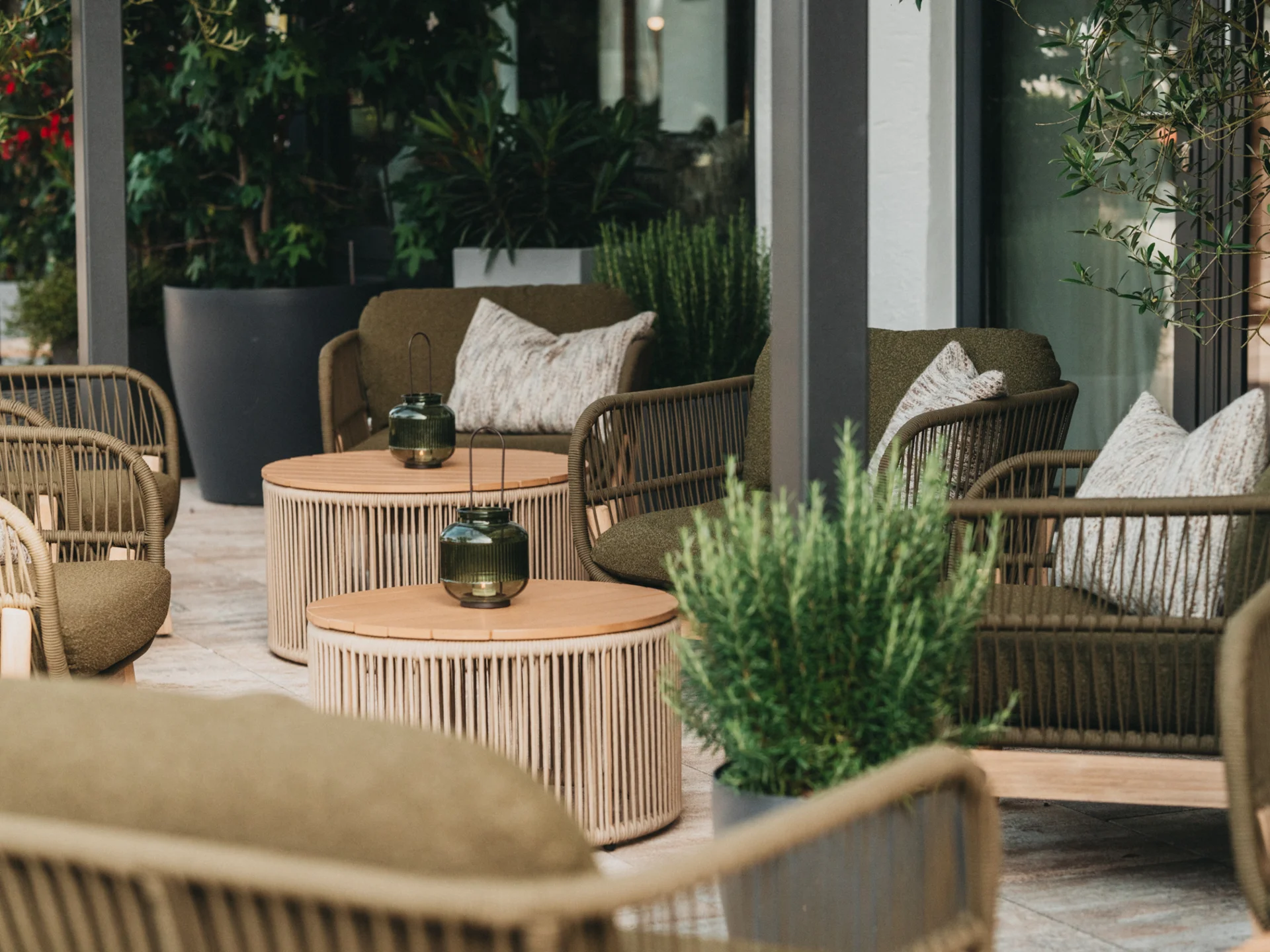 Gemütliche Outdoor-Lounge mit grünen Sesseln und runden Holztischen