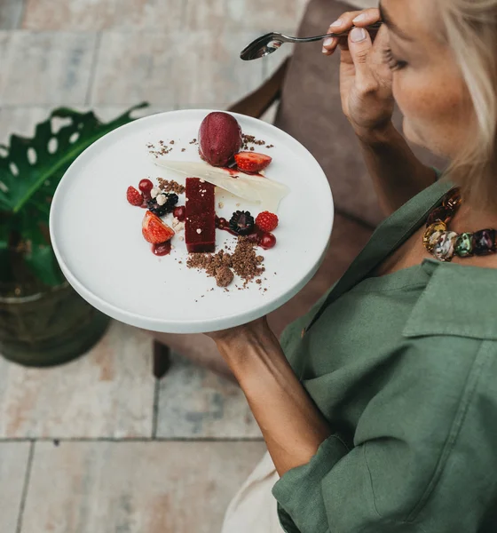 Frau hält Teller mit Dessert aus Beeren und Schokolade