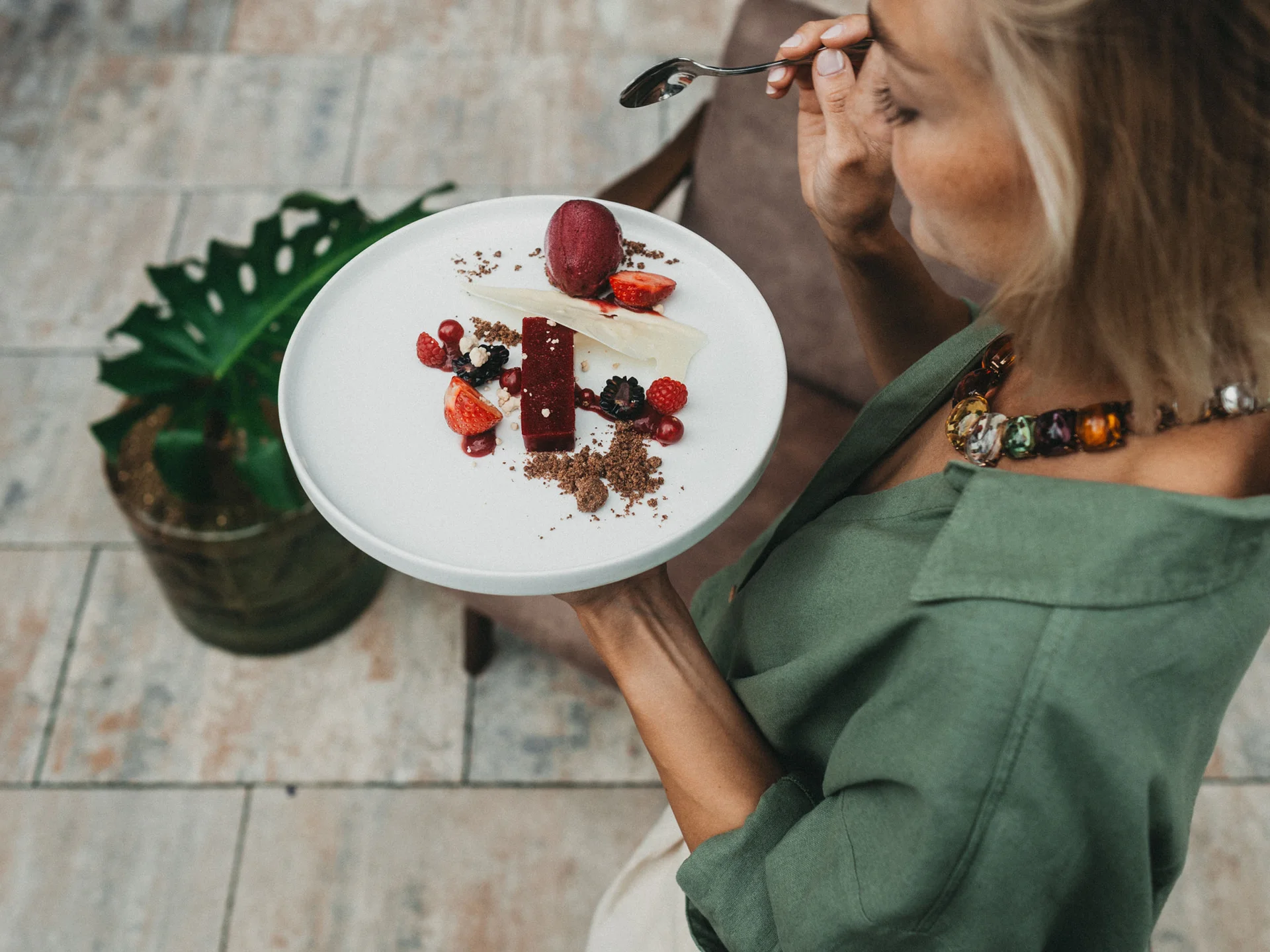 Frau hält Teller mit Dessert aus Beeren und Schokolade