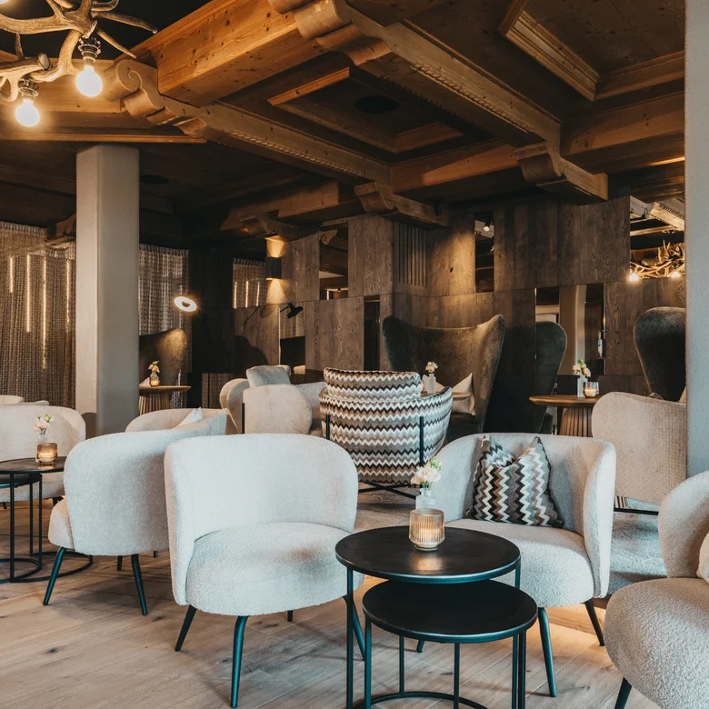 Gemütlicher Hotel-Lounge-Bereich mit beigen Sesseln und Holzbalkendecke