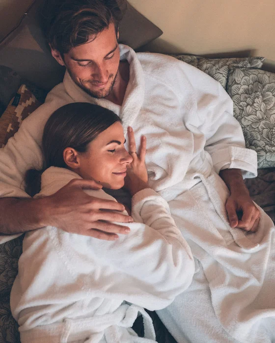 Paar in weißen Bademänteln entspannt sich zusammen auf einem Bett