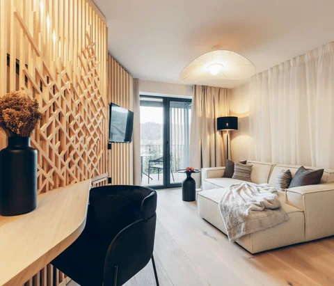 Modern eingerichtetes Wohnzimmer mit Sofa, TV, Schreibtisch und Balkon