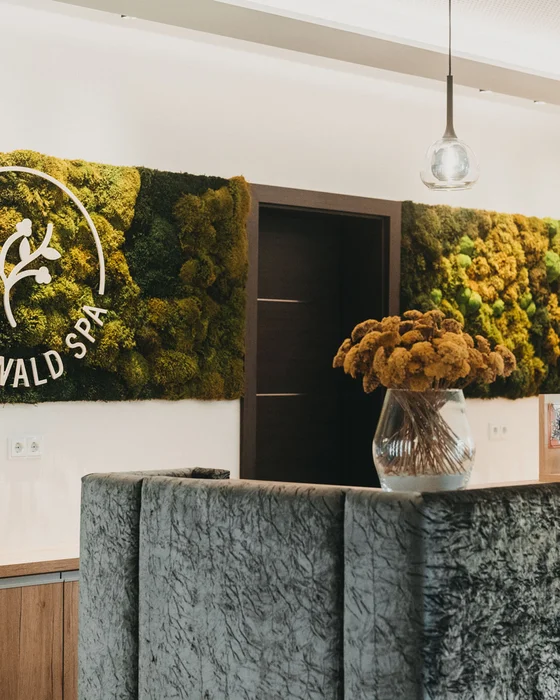 Rezeption im Wald Spa mit Mooswand und Blumenstrauß in Vase