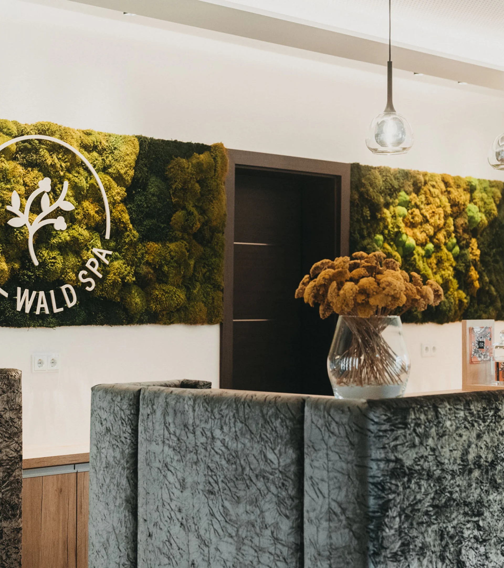 Rezeption im Wald Spa mit Mooswand und Blumenstrauß in Vase