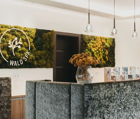 Rezeption im Wald Spa mit Mooswand und Blumenstrauß in Vase