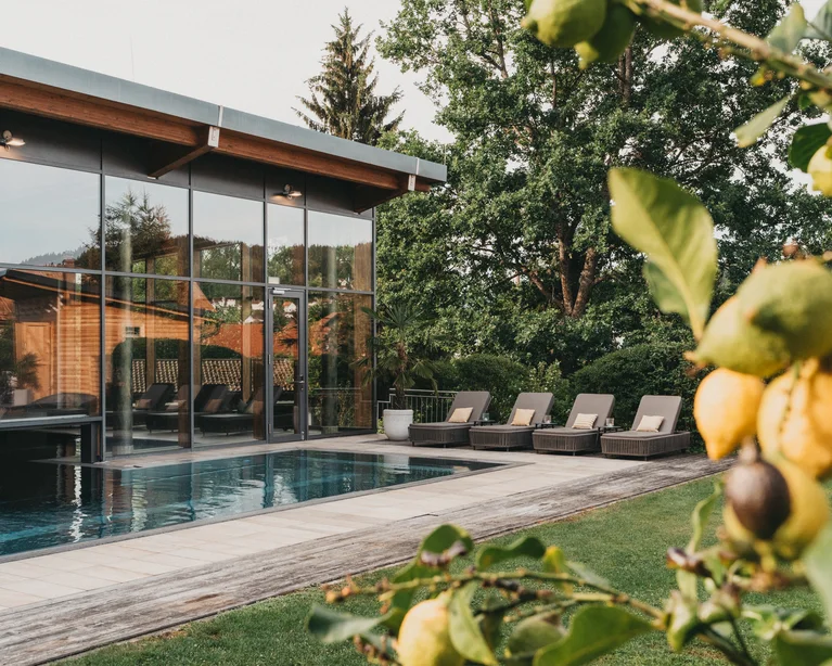 Moderner Poolbereich mit Liegestühlen und Glasfassade in einem Garten