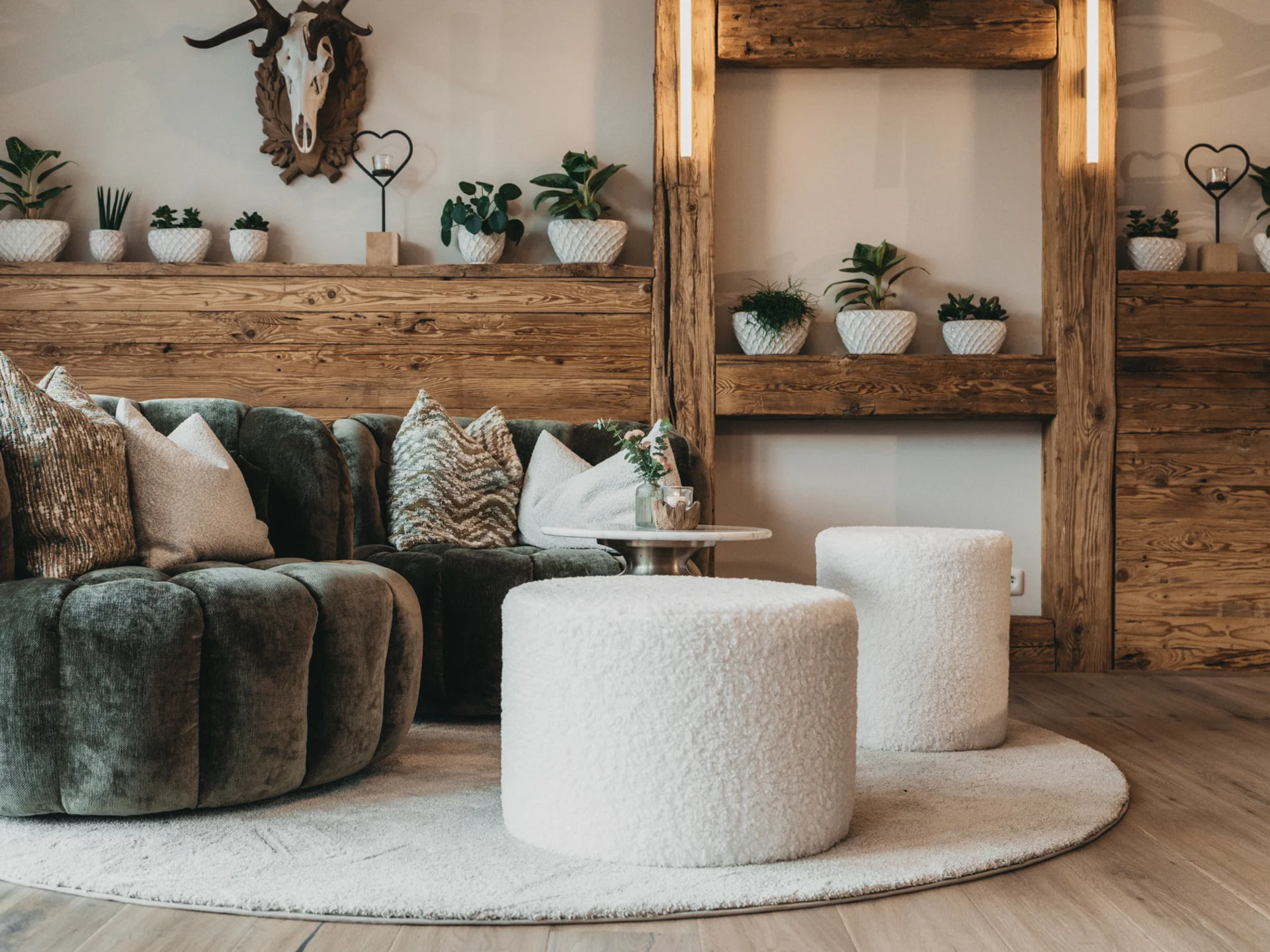 Gemütliche Sitzecke mit grünem Sofa, weißen Hockern und Holzdekor
