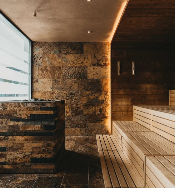 Modern sauna room with wooden benches and stone cladding