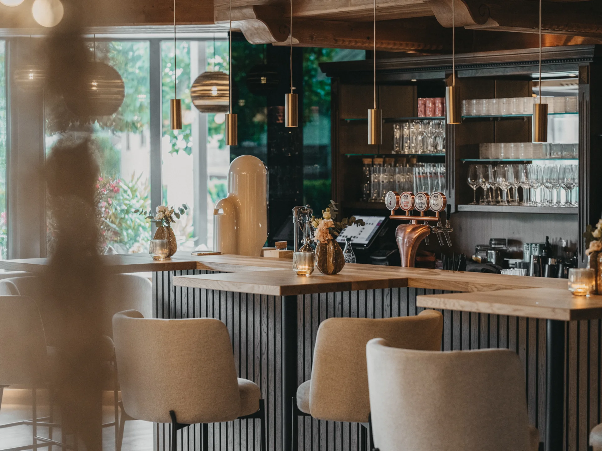 Moderner Barbereich mit Holztheke, Hockern und Glasregalen im Hintergrund