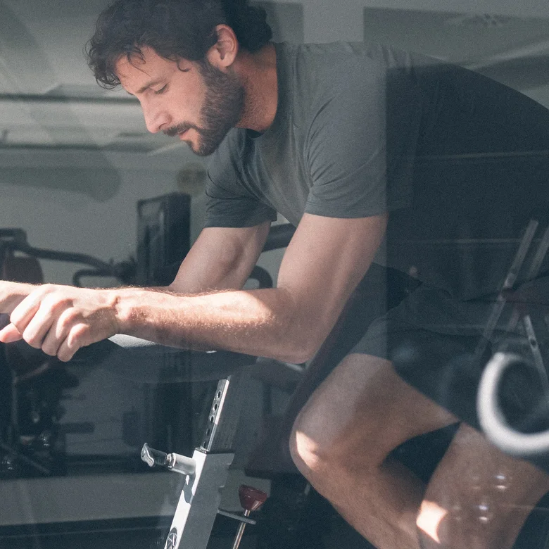 Mann trainiert auf einem Heimtrainer im Fitnessraum
