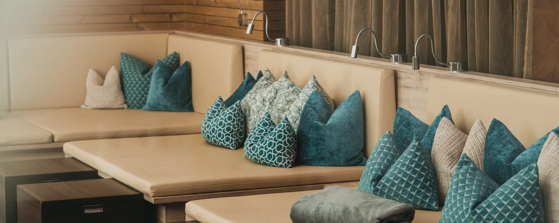 Beige Lounge mit blauen und gemusterten Kissen und kleinen Holztischen
