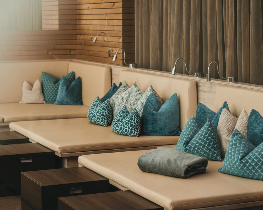 Beige Lounge mit blauen und gemusterten Kissen und kleinen Holztischen