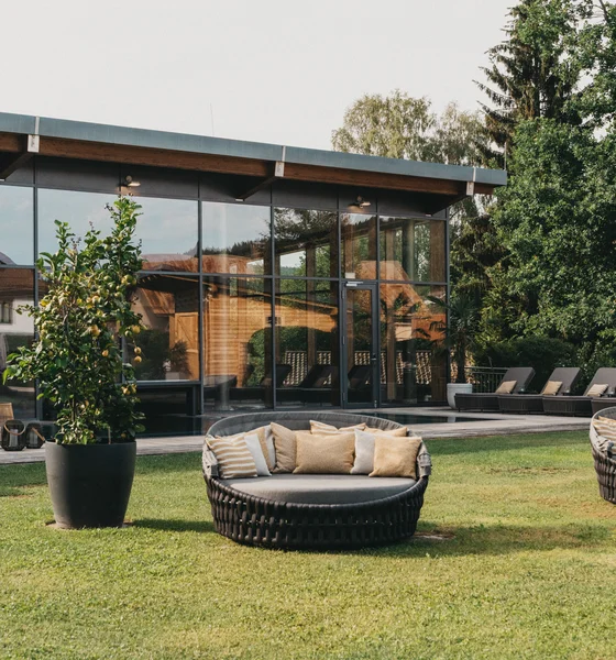 Moderne Terrasse mit runden Lounge-Sesseln und Glasfassade im Garten