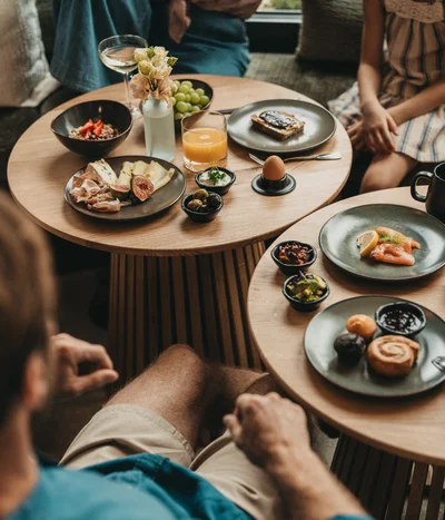 Breakfast table with various foods and drinks, people sitting around it