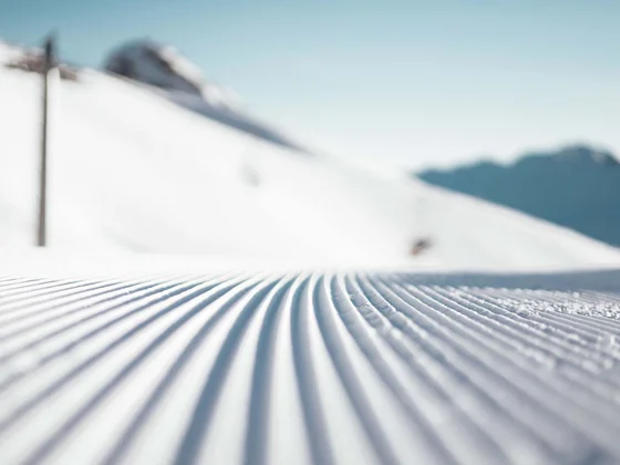 Frisch präparierte Skipiste mit Bergen im Hintergrund