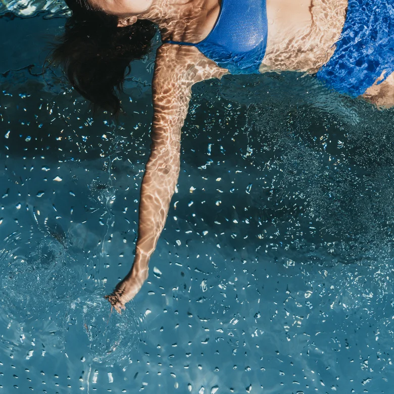 Frau im blauen Bikini schwimmt im klaren Wasser