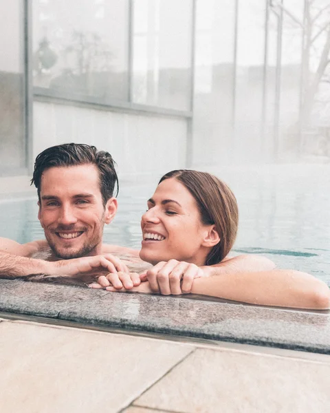 Paar entspannt sich im beheizten Außenpool eines modernen Spas