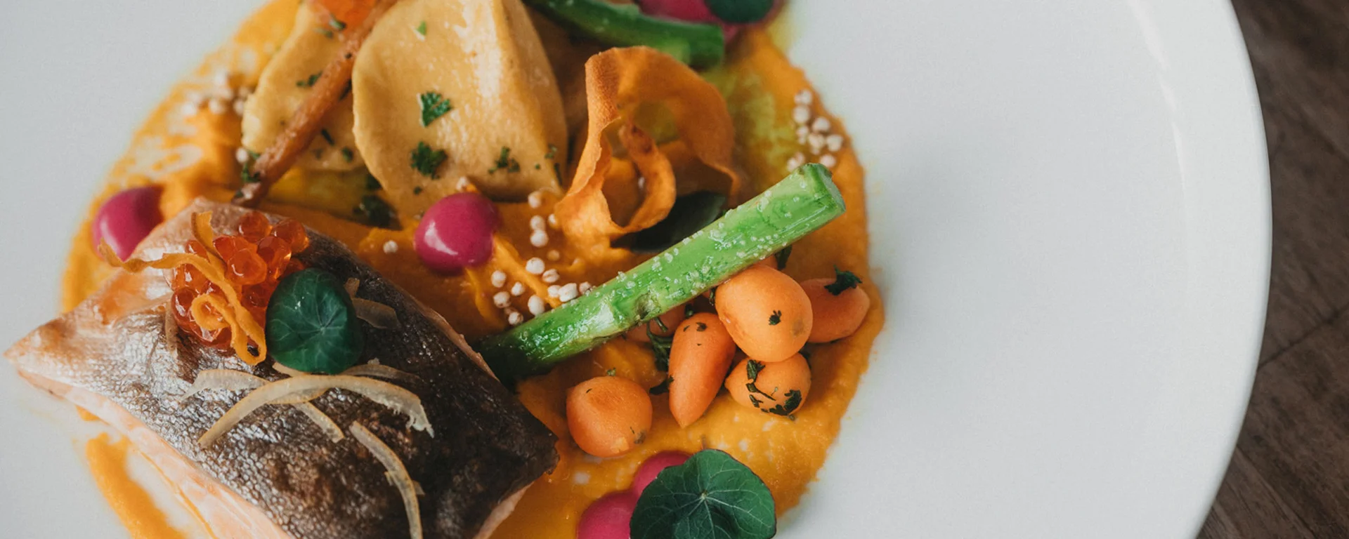 Gourmetgericht mit gebratenem Fisch, Spargel und Gemüse auf weißem Teller