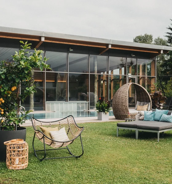 Moderner Garten mit Lounge-Möbeln und Swimmingpool vor Glasgebäude