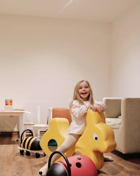 Fröhliches Mädchen spielt auf gelbem Hasen-Spielzeug im Wohnzimmer