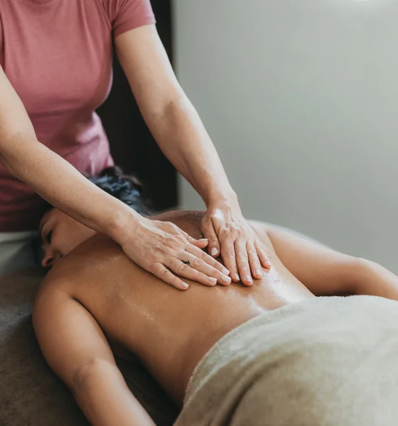 Frau erhält Rückenmassage auf Massagetisch in hellem Raum