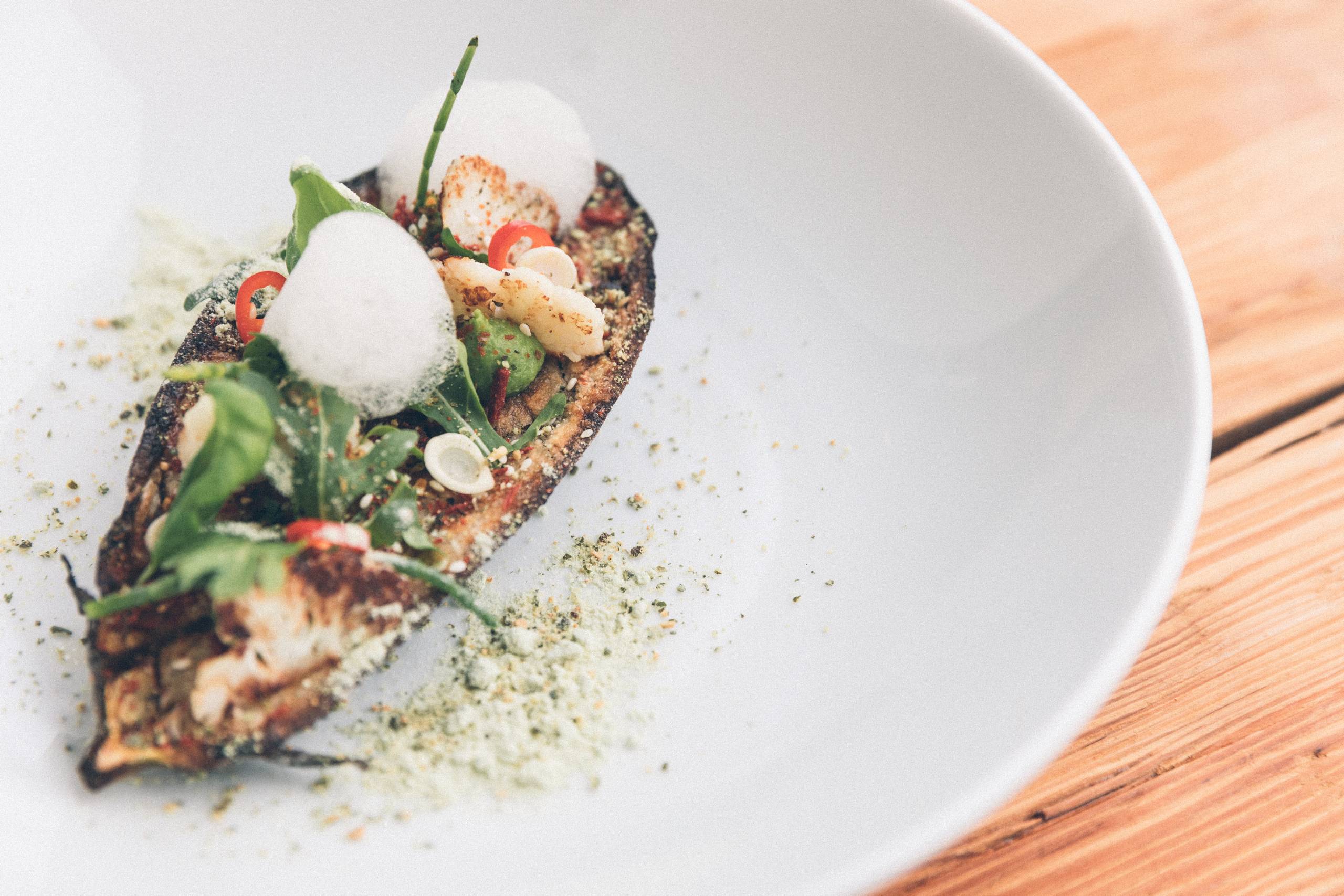 Gourmet dish with grilled vegetables, leaf salad and foam on a white plate